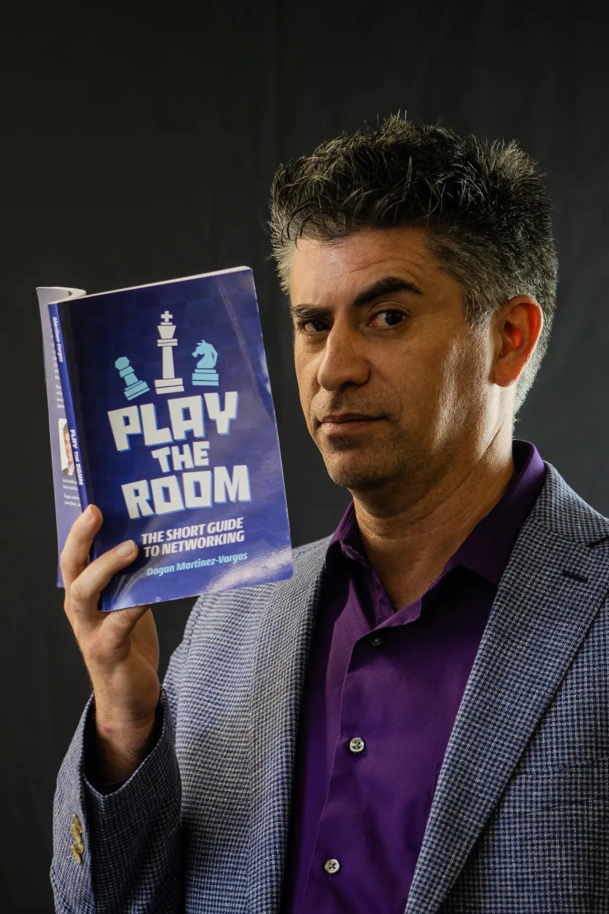 Dagan Martinez-Vargas holding his book, Play the Room: The Short Guide to Networking