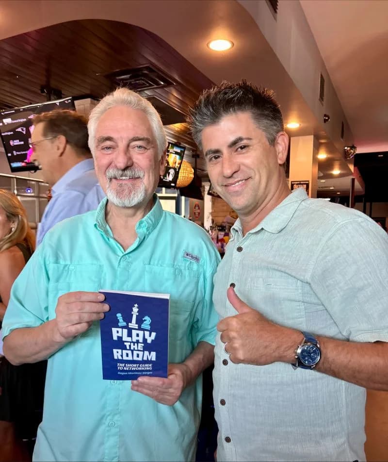 Dagan Martinez-Vargas with Dr. Ivan Misner, founder of BNI, holding a copy of Play the Room